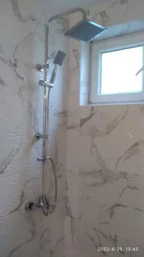 Shower enclosure with marble-pattern tiles and a modern faucet. - image 4