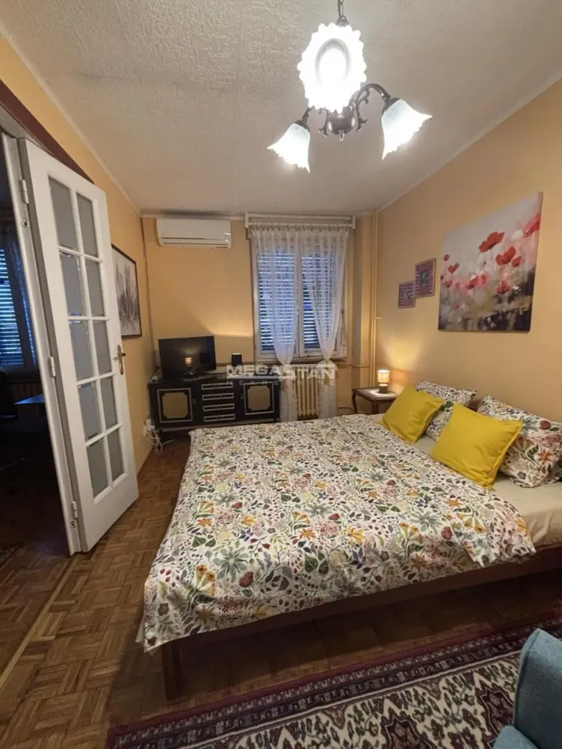 Furnished bedroom with a double bed, dresser, and air conditioning unit.