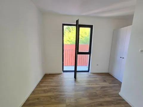 Prazna soba sa bijelim zidovima, drvenim podom i izlazom na terasu. - image 6