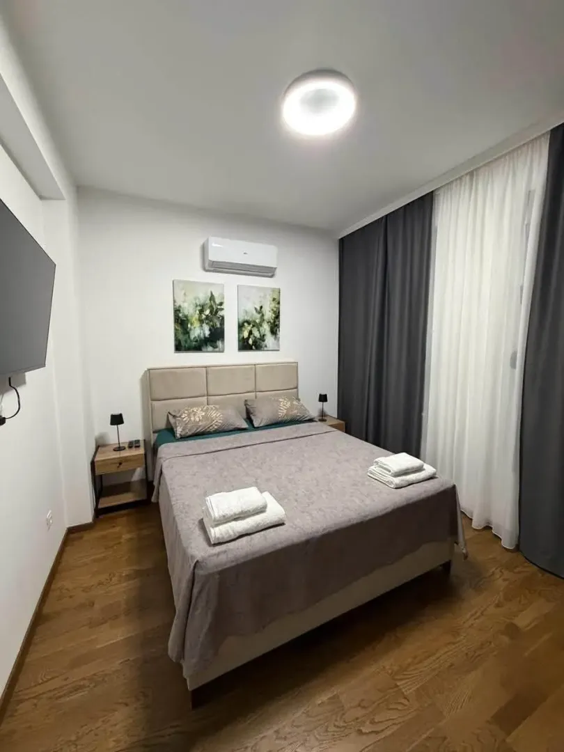 Uređena spavaća soba sa bračnim krevetom i zavesama.