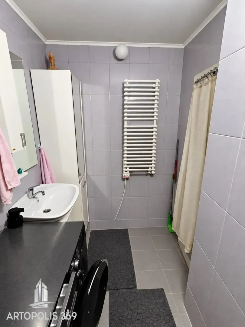 Kupatilo obloženo keramičkim pločicama sa umivaonikom i radijatorom.