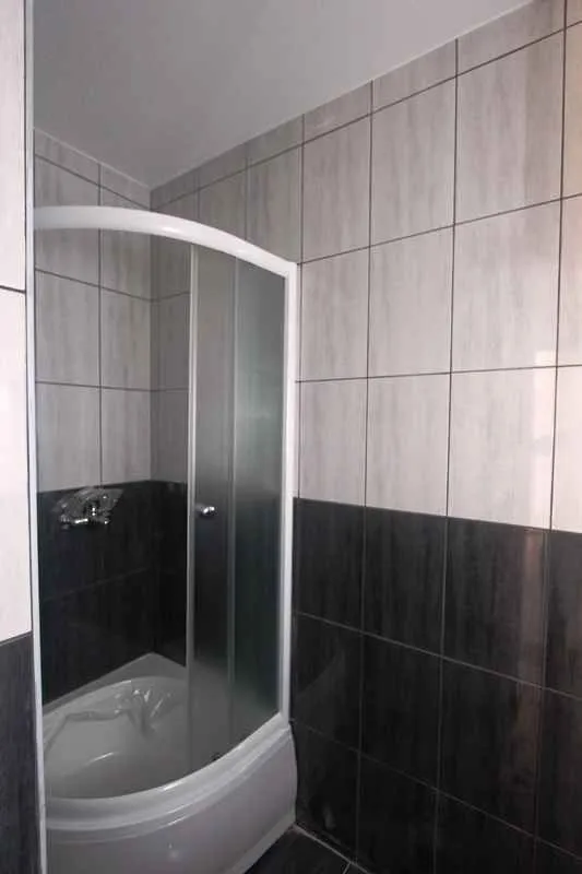 Kupatilo sa tuš kabinom obloženo keramičkim pločicama.
