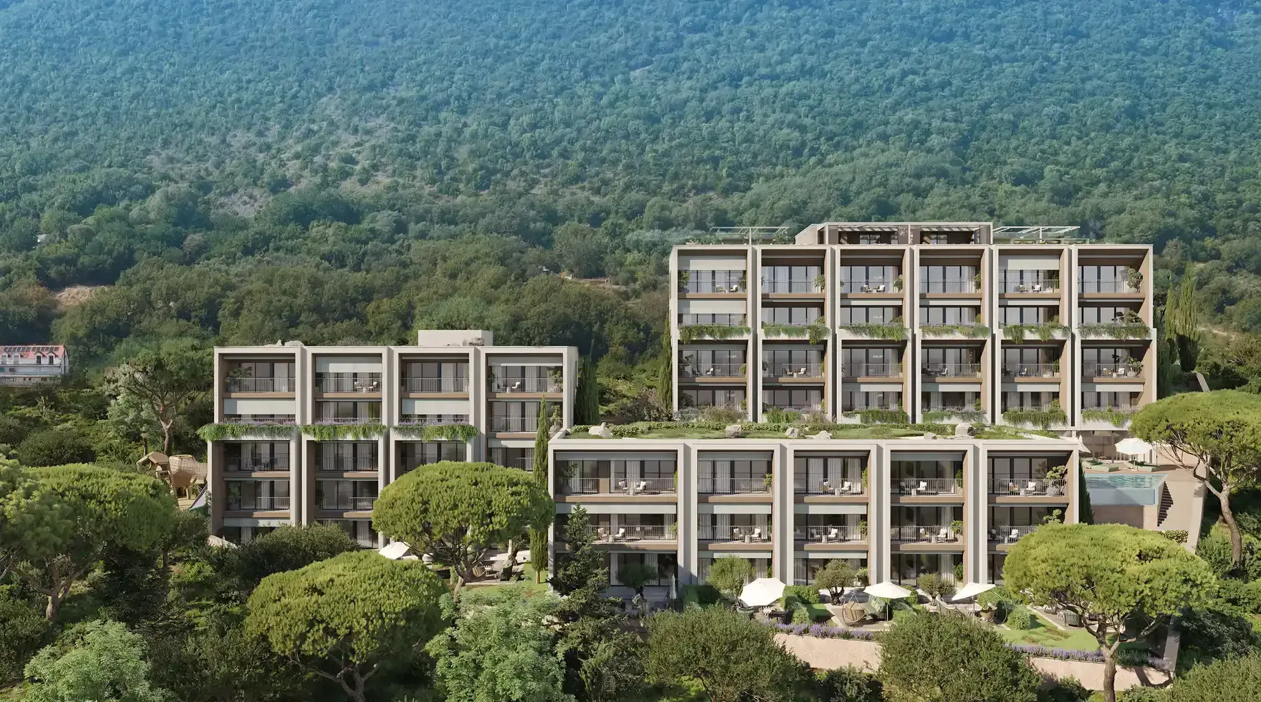 Prikaz eksterijera modernog stambenog kompleksa u zelenilu sa planinskom pozadinom.