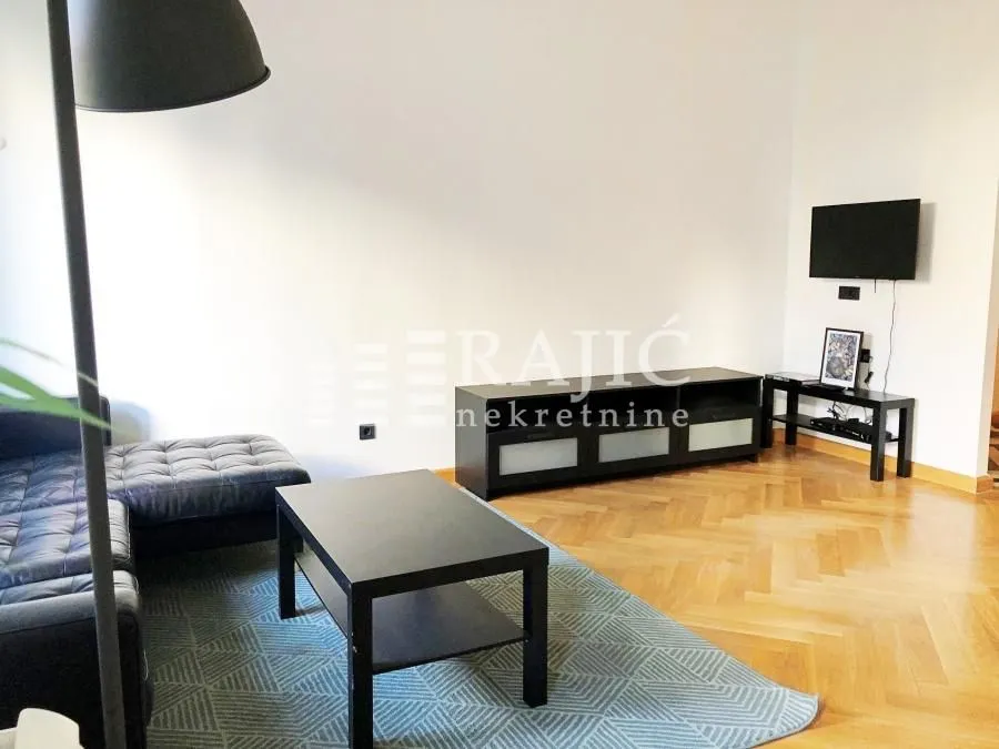 Living room with a sofa, coffee table and wall-mounted TV.