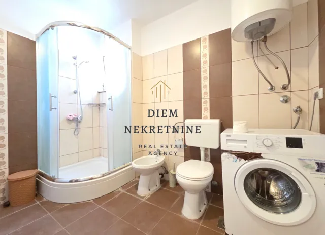 Bathroom with a shower cabin, sanitary ware, and a washing machine.