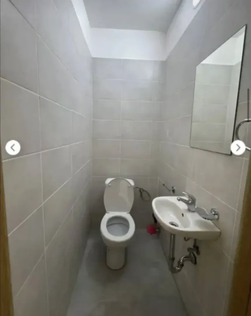 Small bathroom tiled in light colors with a toilet and a washbasin.