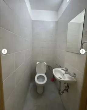 Small bathroom tiled in light colors with a toilet and a washbasin. - image 11