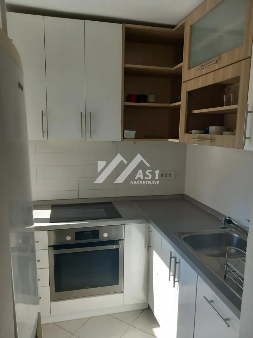 Small kitchen with built-in oven, hob, and sink.