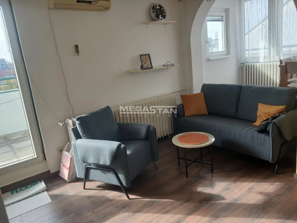 Dnevna soba sa sivom garniturom, foteljom i stočićem.