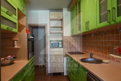 Kitchen equipped with green cabinets, built-in oven, and a sink. - image 7