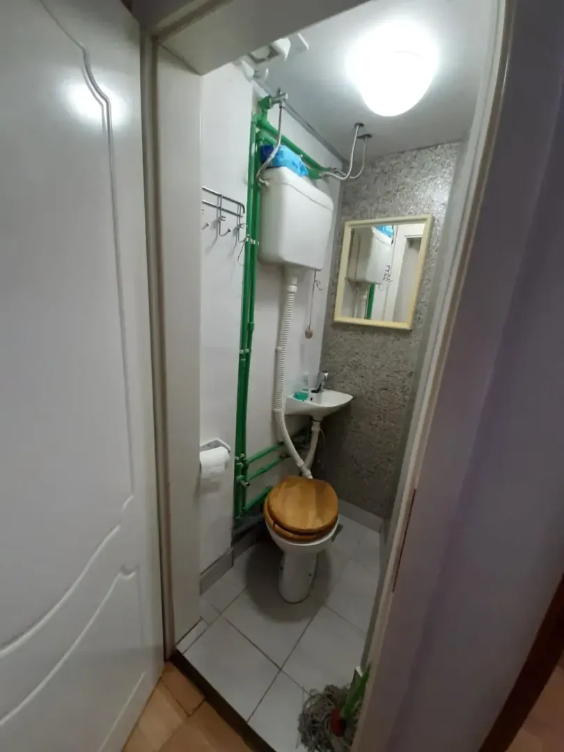 Manje kupatilo sa wc šoljom, umivaonikom i ogledalom.