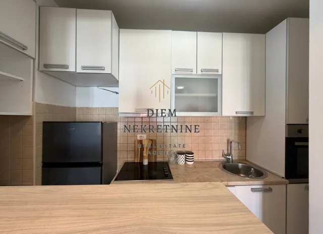 Small equipped kitchen with white cabinets and a refrigerator.