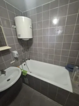 Manje kupatilo obloženo sivim pločicama sa kadom i bojlerom. - image 10
