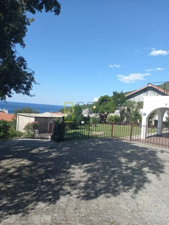 Popločano dvorište sa pogledom na more i zelenilo.