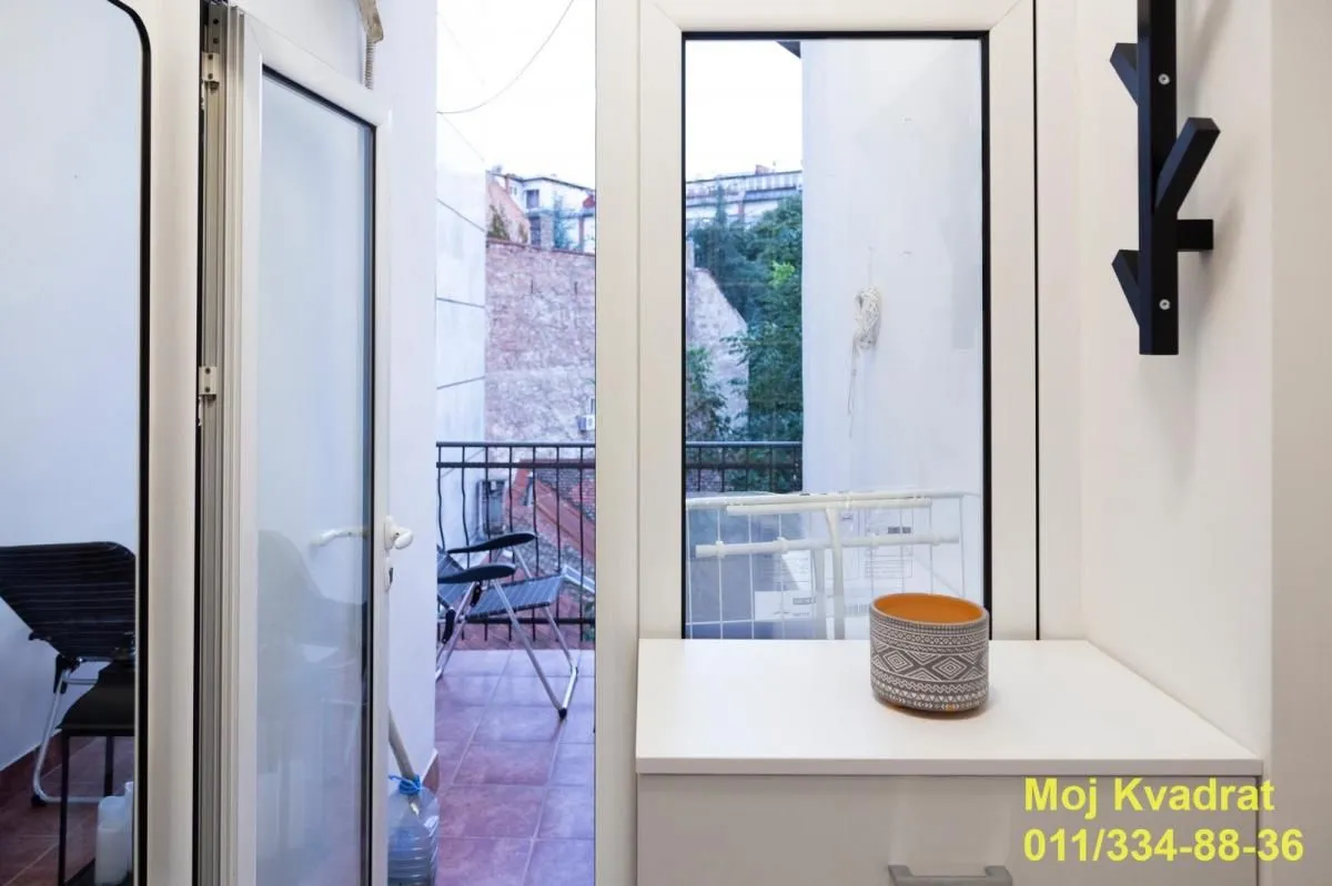 View through the balcony door to the terrace and surrounding buildings.