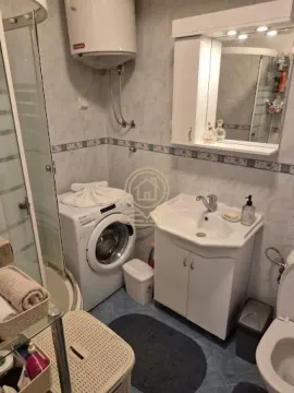 A compactly equipped bathroom with a shower cabin, washbasin, and washing machine. - image 4