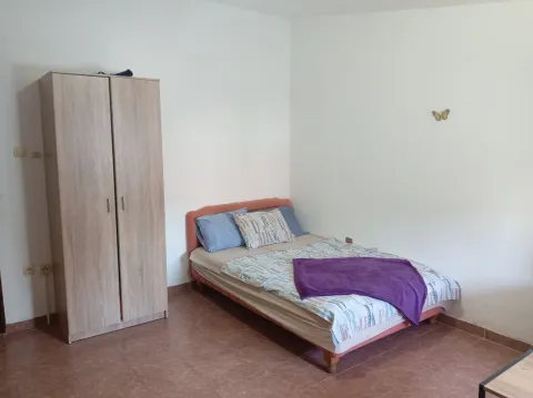 Simply furnished bedroom with a bed and a wooden wardrobe. - image 3