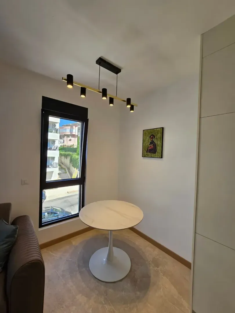 Small dining table with a modern chandelier and a window overlooking the street.