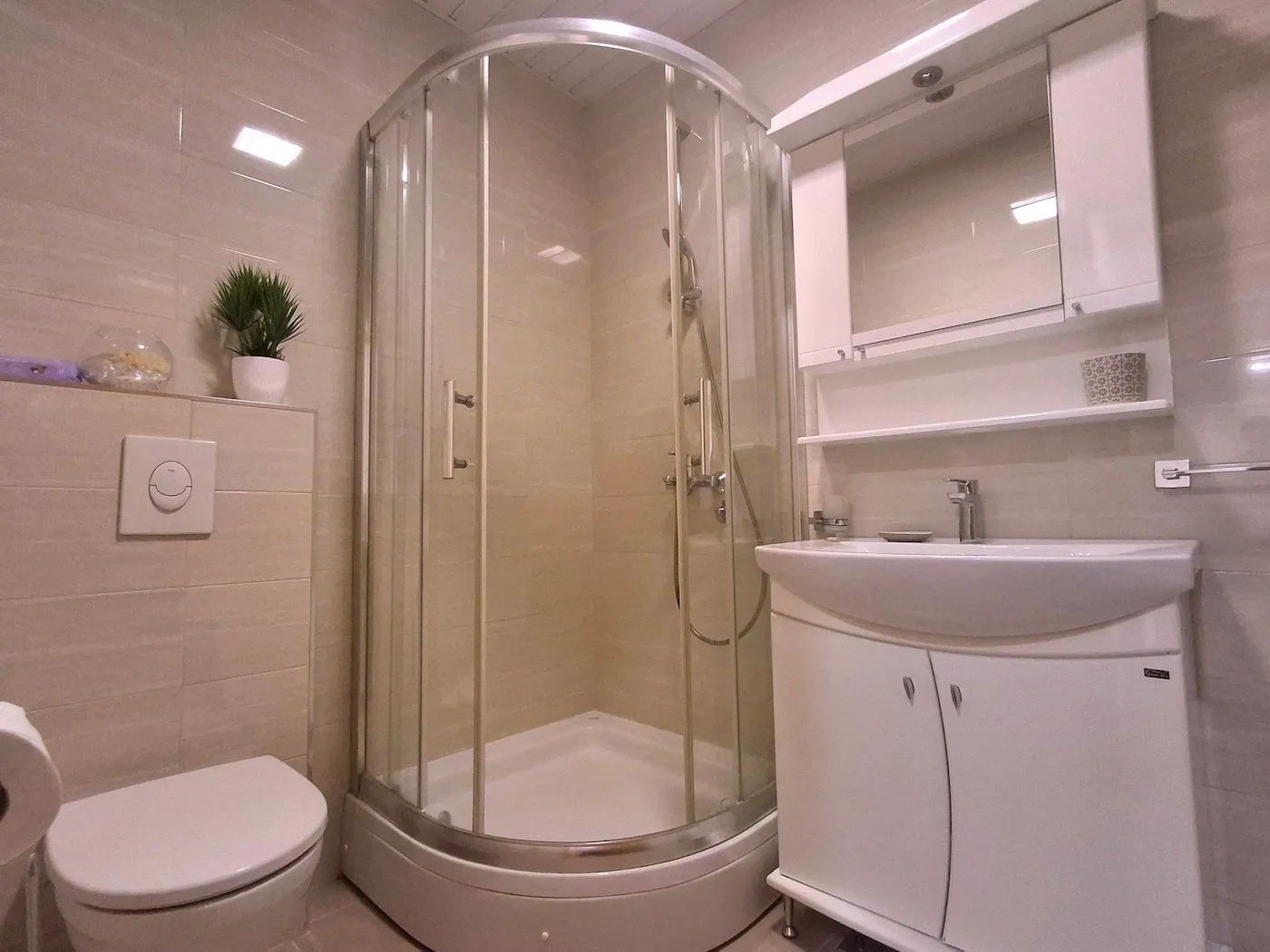 Furnished bathroom with a shower cabin, sink, and toilet.