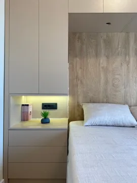View of the bed and built-in wardrobe with an illuminated niche in the bedroom. - image 19