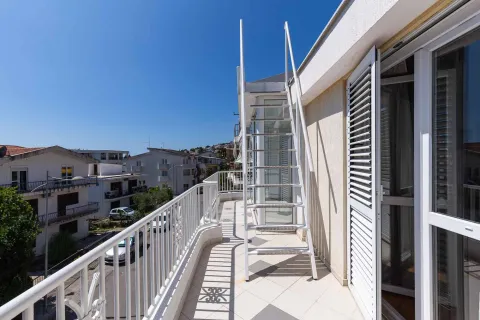 Dugačak balkon sa metalnim stepenicama i pogledom na okolne zgrade i ulicu. - image 23