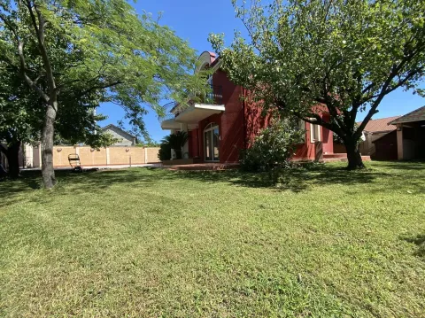 A yard with a green lawn in front of a red house. - image 11