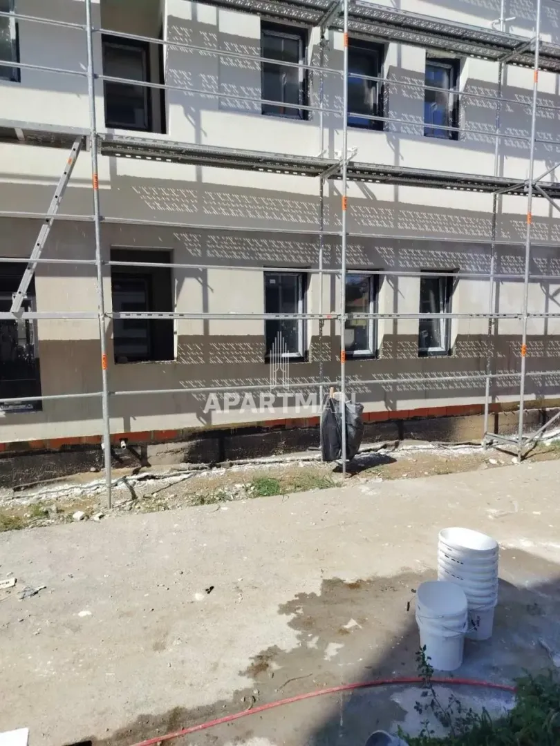 Pogled na spoljašnjost zgrade u izgradnji sa skelama.