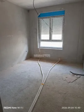 Pogled na neuređenu prostoriju u sivoj fazi izgradnje sa instalacijama i prozorom. - image 4