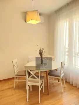 Dining area with a white table and four chairs near the window. - image 15