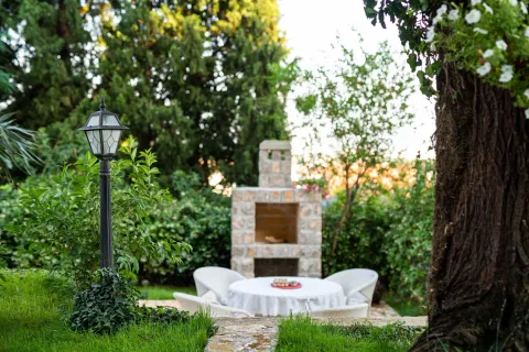Landscaped yard featuring a stone fireplace and outdoor seating. - image 3