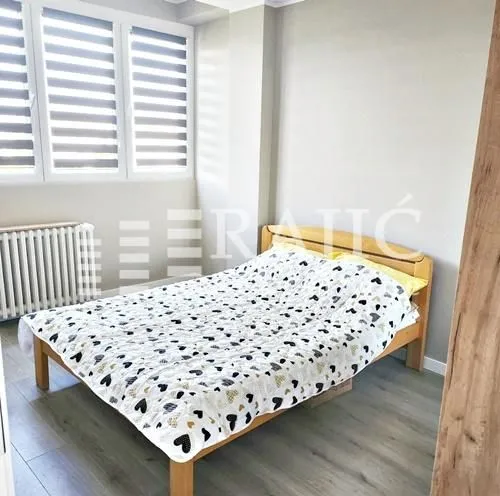 Furnished bedroom with a wooden bed and windows.