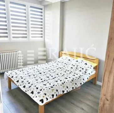 Furnished bedroom with a wooden bed and windows. - image 4