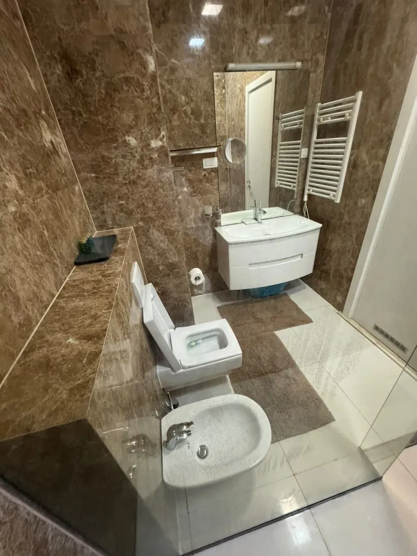 Marble-tiled bathroom featuring a washbasin, toilet, and bidet.
