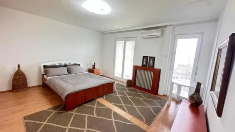 Bedroom with a double bed, wooden flooring, and two terrace doors. - image 5