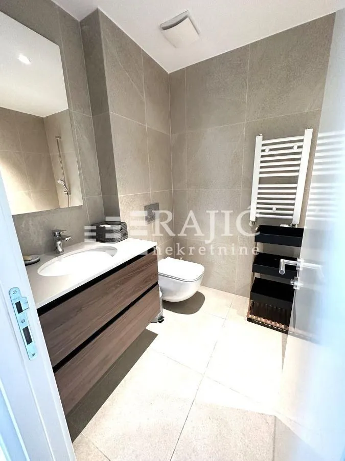 Modern bathroom with a washbasin, toilet, and ceramic tiles.