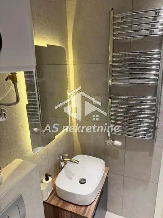 Modern bathroom with a washbasin and a backlit mirror.