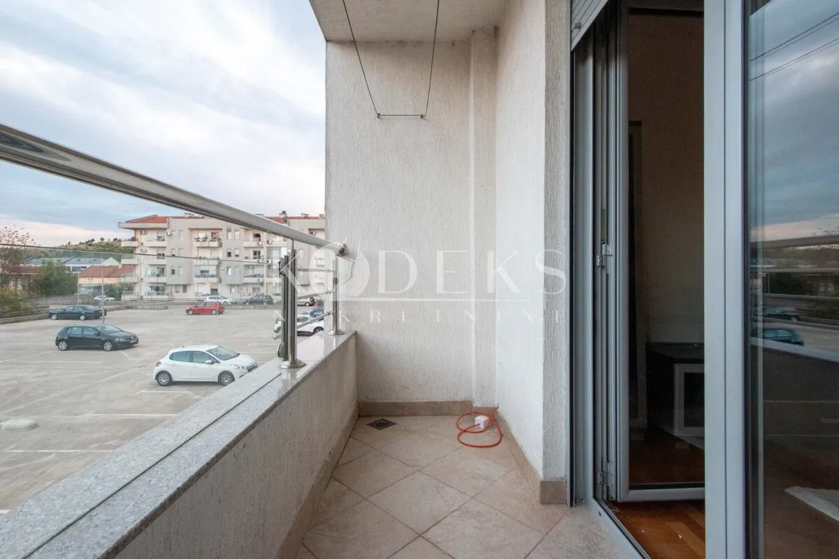 Covered balcony with metal railing and parking view.