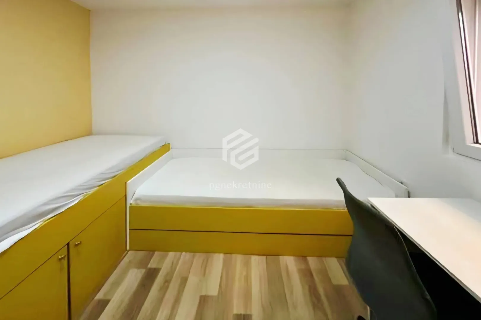 Children's bedroom with two beds and a desk.