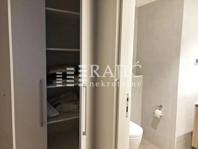 View of the bathroom and a built-in closet with open doors.