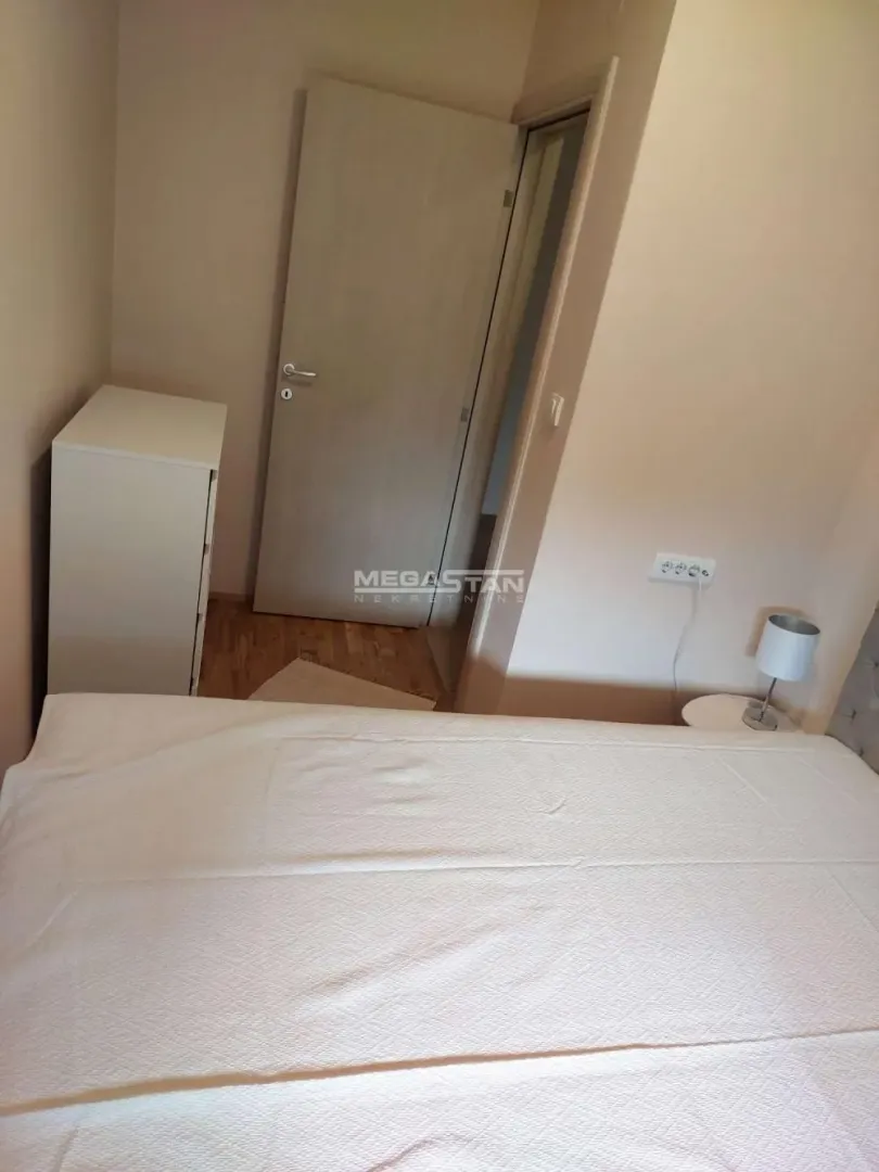 Pogled na spavaću sobu sa bračnim krevetom i vratima.