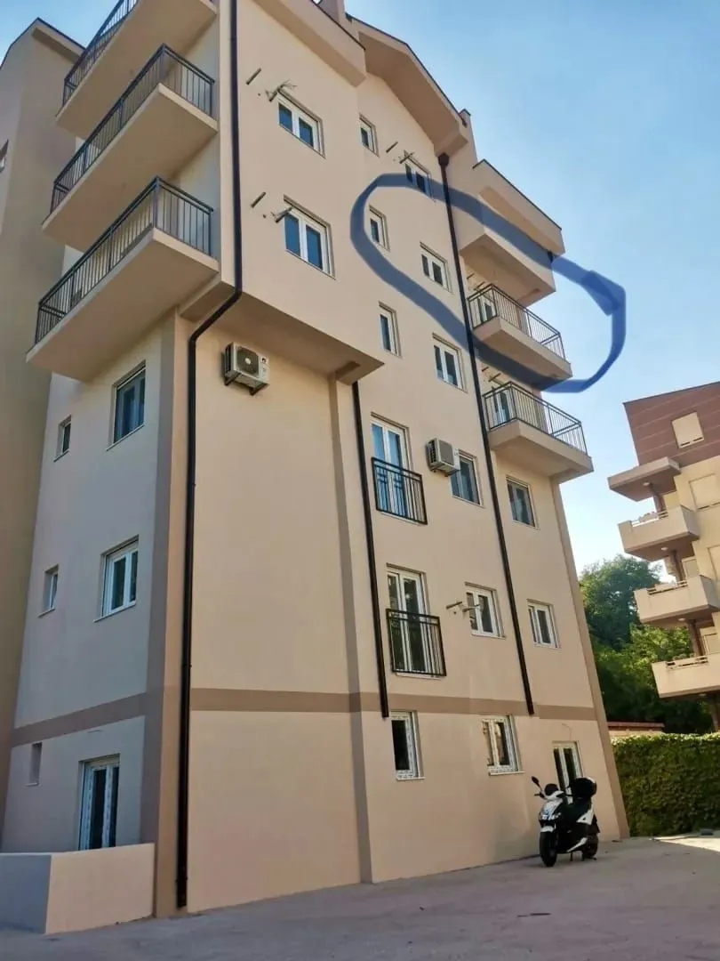 Exterior view of an apartment building with balconies and a marked area on the facade.