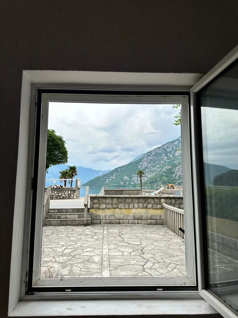 View through the window towards the courtyard, sea, and mountains.