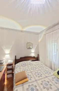 Furnished bedroom with a double bed, bedside tables, and a window with curtains. - image 7