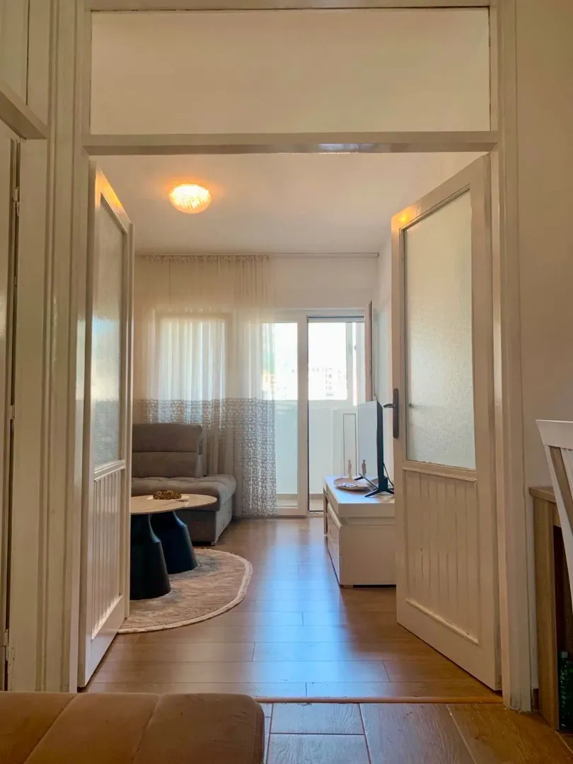 View of the bright living room through open doors from the hallway.