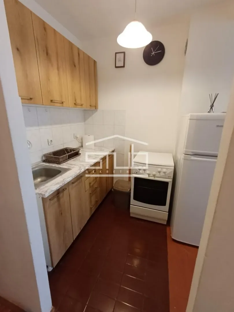 Small kitchen with wooden cabinets, a stove, and a refrigerator.