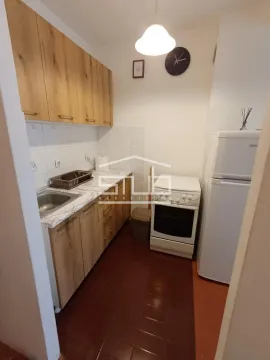 Small kitchen with wooden cabinets, a stove, and a refrigerator. - image 6