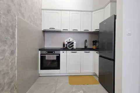 Small kitchen with white cabinets and a dark refrigerator. - image 6