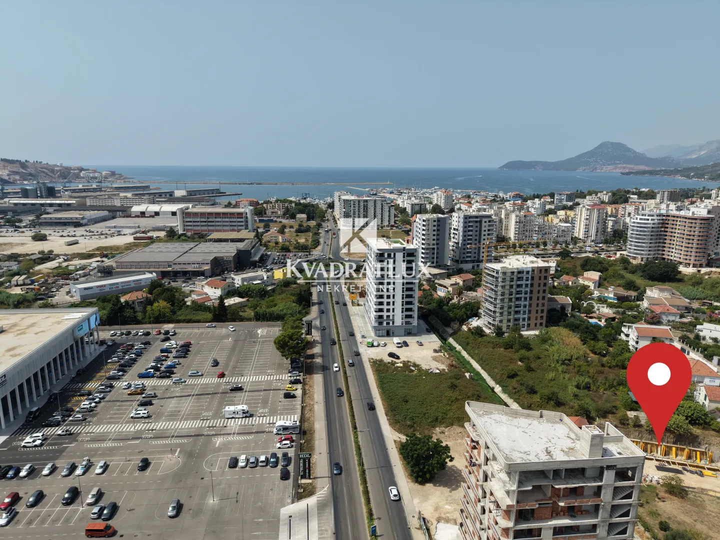 Pogled iz vazduha na grad, luku i more sa označenom lokacijom nekretnine.