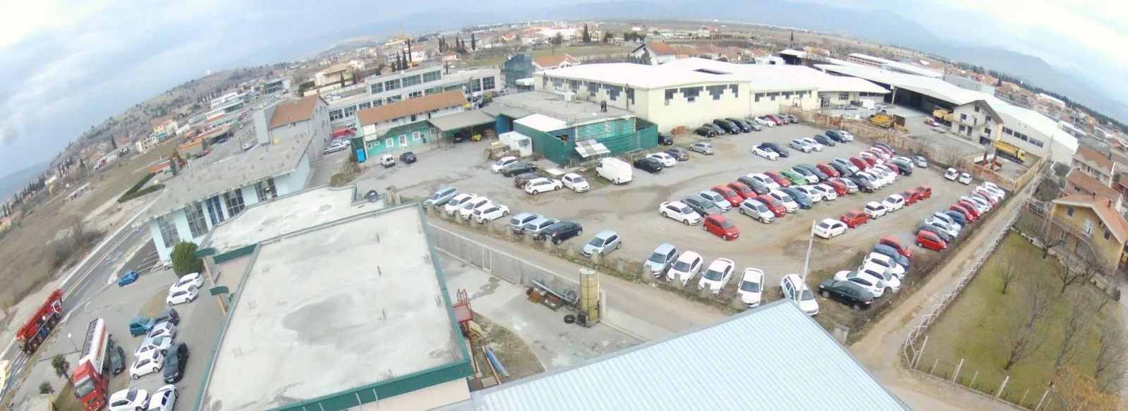 A wide-angle view of a commercial complex featuring a large parking lot and surrounding buildings.
