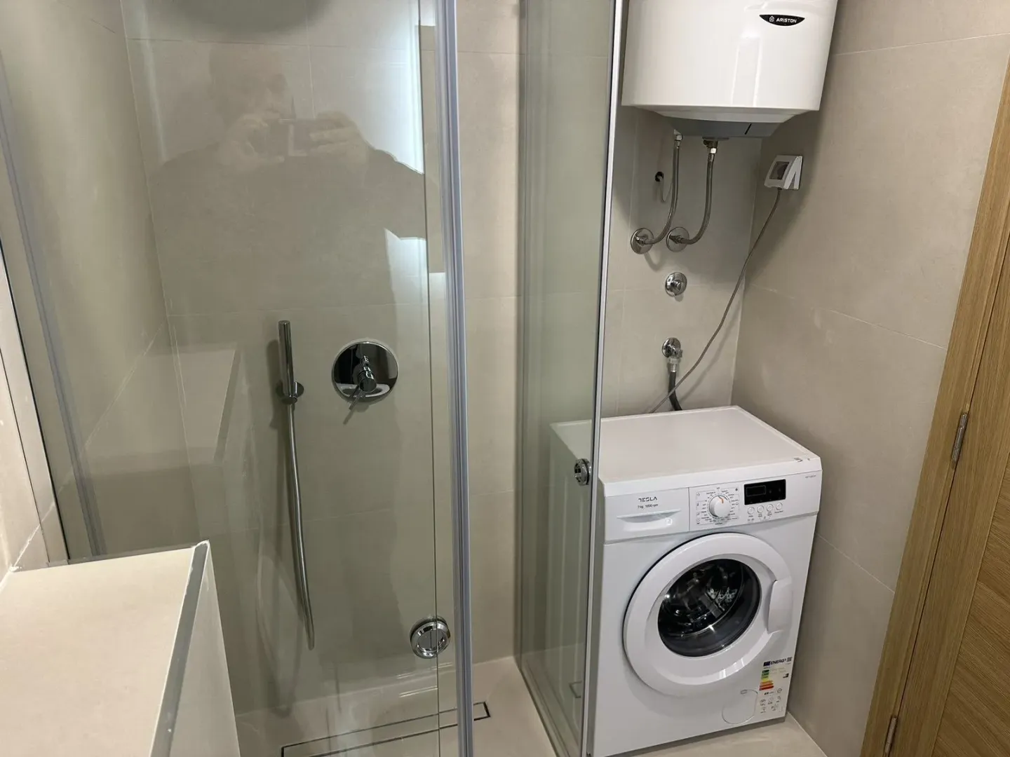 Modern bathroom with a shower cabin, washing machine, and boiler.